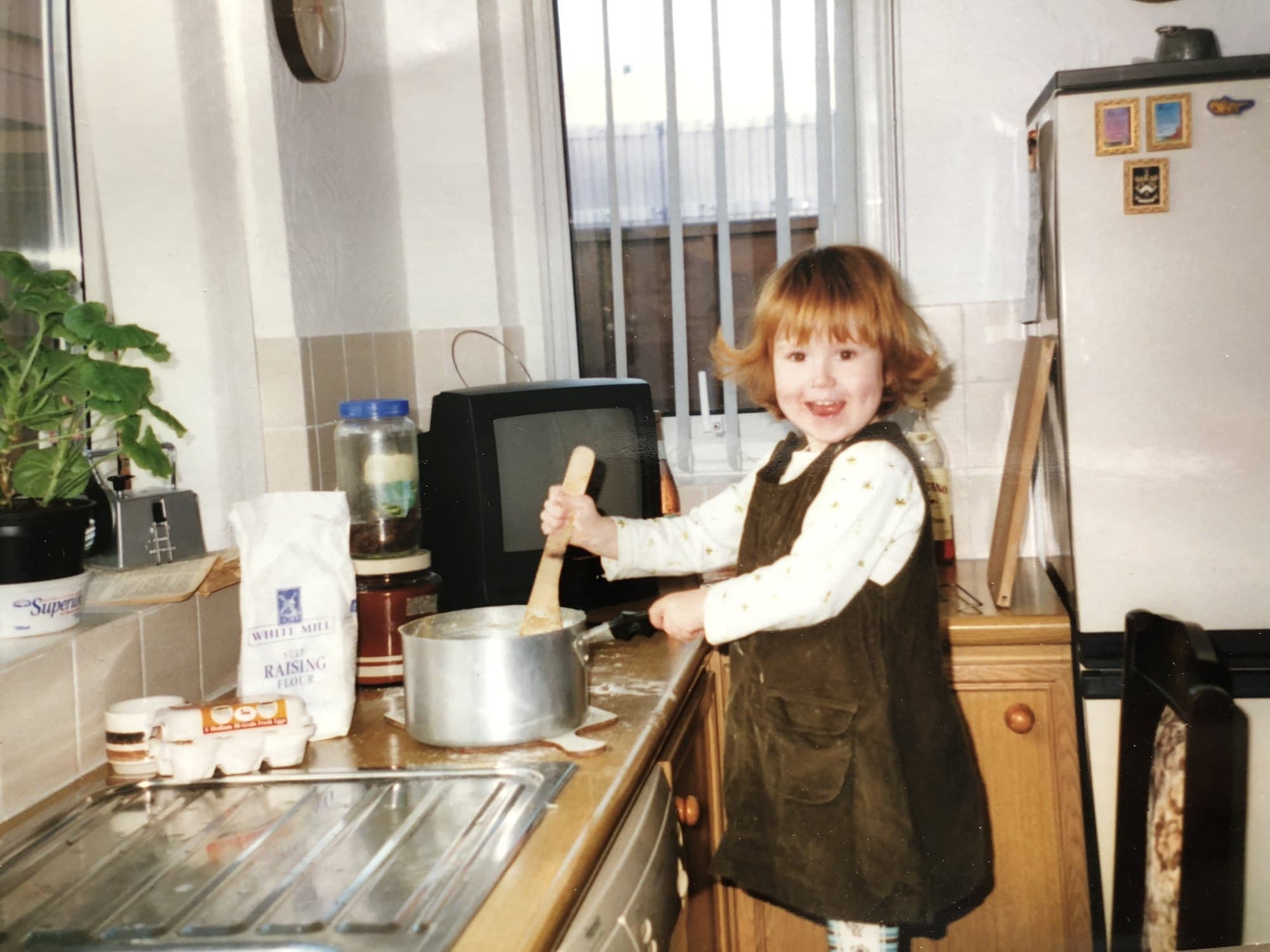 Georgia as a little girl, stirring a pan in her nan's kitchen
